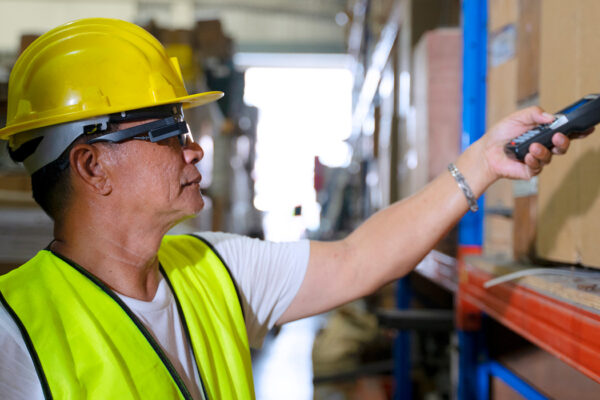 Werknemer heeft een augmented reality bril op in een magazijn en scant een pakket.